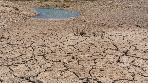 Dried-up cracked soil next to a receding puddle.