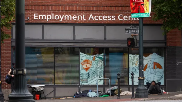 Unhoused people camped in front of brick building with "Employment Access Center" sign in Portland, Oregon.