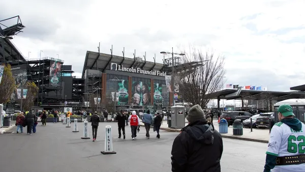 People walking toward Lincoln Field football stadium in Philadelphia in Eagles gear.