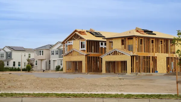 Wood-frame houses under construction next to completed houses.