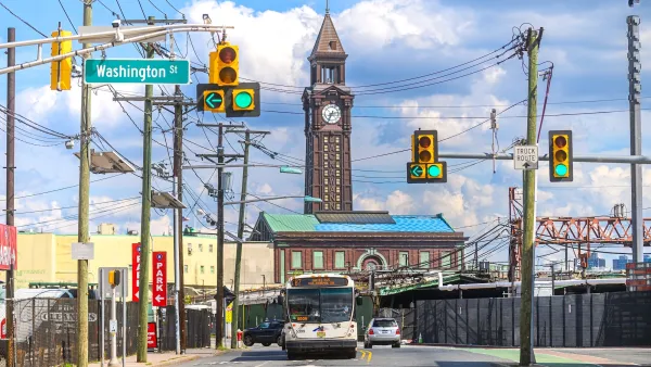 Street in Hoboken, New Jersey with old brick building with clock tower in background and public bus driving toward camera.