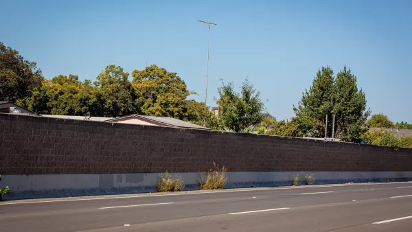 Concrete sound wall next to empty freeway.