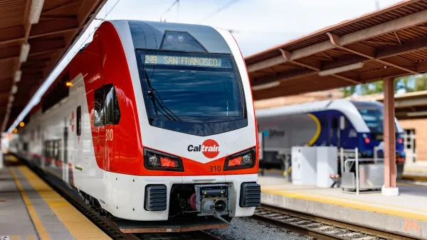 ELectric red and white Caltrain train at outdoor covered platform.