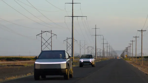 Two silver Cybertrucks driving down rural road with fog,