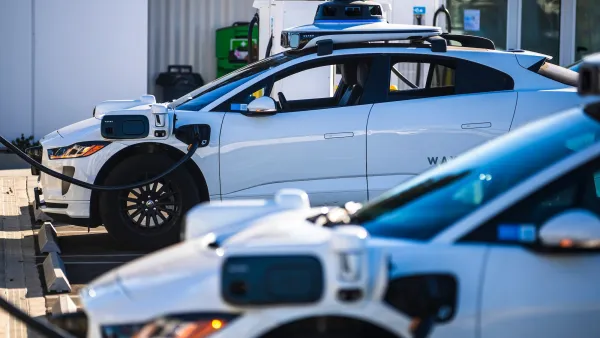White Waymo cars parked at charging station.