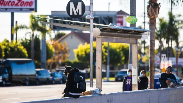 People waiting at a Los Angeles Metro bus stop with black and white M logo.