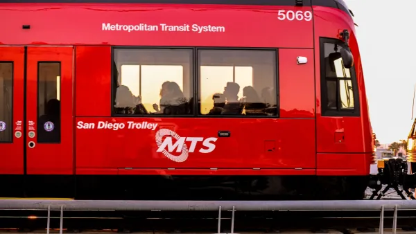 Red San Diego light rail train with people visible inside.