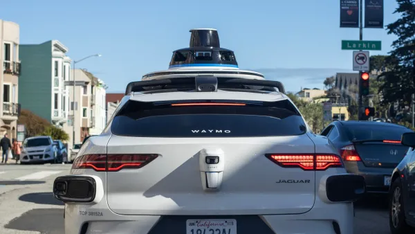 White Waymo self-driving car in San Francisco, CA at red traffic light.