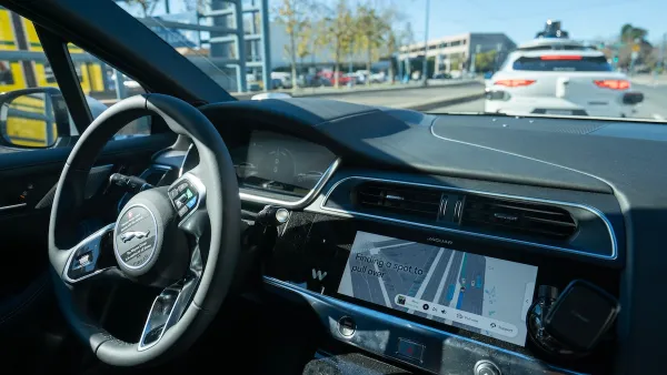 Interior of self-driving car with white car in front of it on the road.