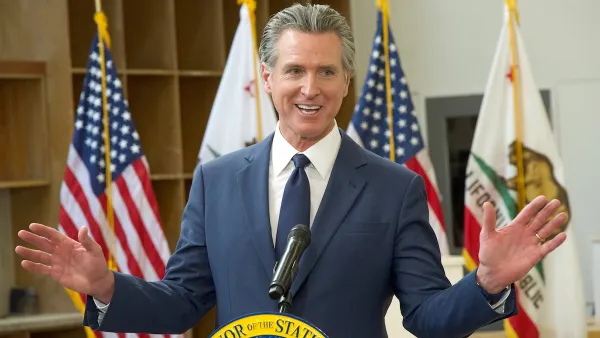 Gavin Newsom gesturing with both hands out behind a podium.