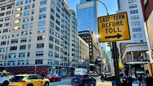 Yellow "last turn before toll" sign on post on busy street in New York City.