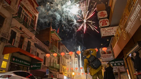 Fireworks going off above San Francisco urban street.