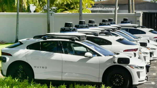 White Waymo self-driving cars parked in a row in Miami, Florida.