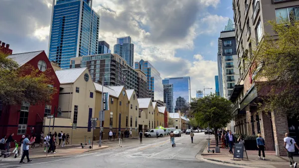 Street with two-story apartment buildings in Austin, Texas with downtown skyline visible in background.