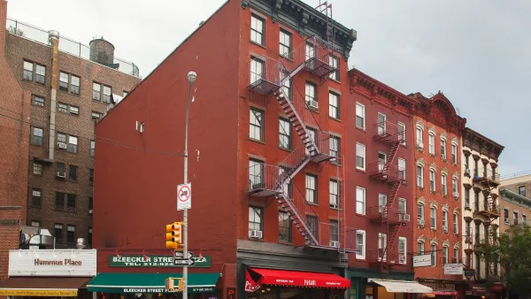 Red brick building in Greenwich Village, New York City with pizza shop and other retail on ground floor.