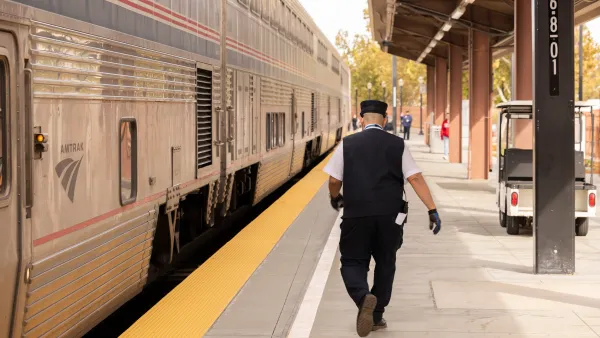 An Amtrak conductor walks parallel to an Amtrak train. 