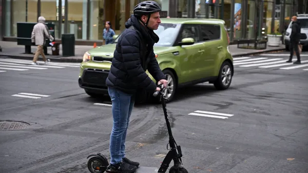 A man wearing a helmet rides an e-scooter on a street in Manhattan.