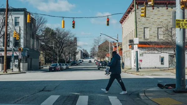 A person crossing a street under hanging traffic lights in Maryland.