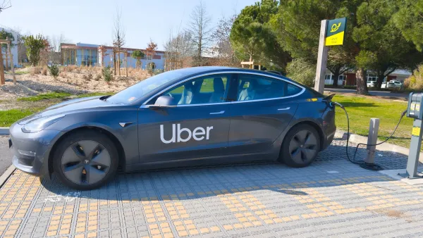 Dark grey Tesla car with Uber logo on side plugged into charger outdoors in Bordeaux, France.