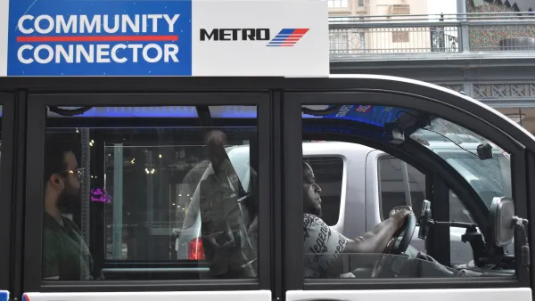 A modern Metro Community Connector (Cab) EV Vehicle, cruising during midday with a passenger in the downtown financial district area.