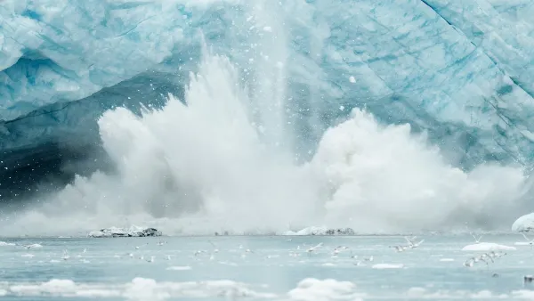 An iceberg from a glacier falls into an ocean.