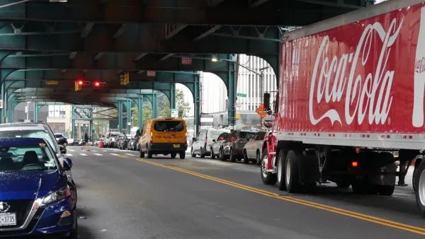 Red Coca Cola truck driving under elevated rail track in New York City.