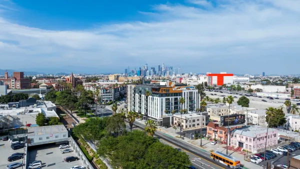 Downtown Los Angeles skyline in background with mid-rise apartment buildings in foreground as part of sprawled cityscape.