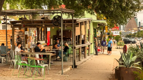 Wooden shops and restaurants in Austin, with people mingling.