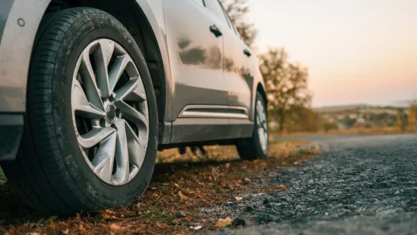 Close-up of rear tire on silver car at sunset.