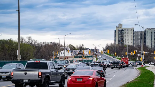 A large road with heavy traffic amidst residential buildings