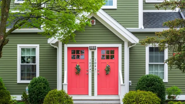 Green traditional duplex with red doors.