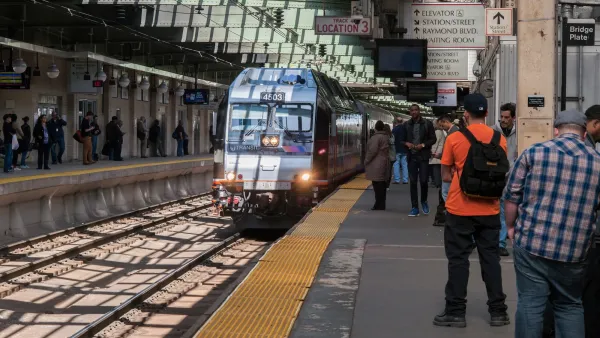 NJ Transit train pulling up to platform with passengers waiting.