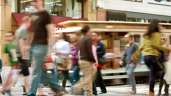 Blurred pedestrians crossing busy crosswalk in San Francisco, California.