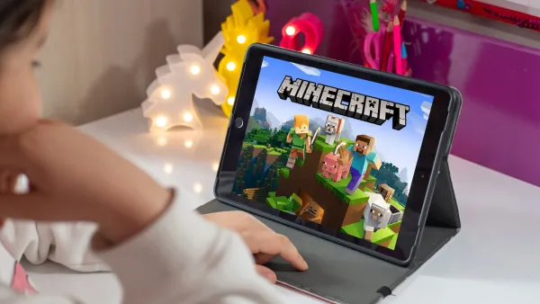 Close-up over shoulder of child looking at Minecraft video game splash page on iPad.