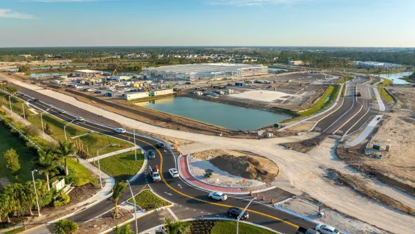 Roundabout under construction with cars moving around one side of it.