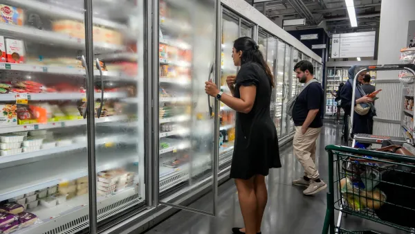 People looking into the frozen foods aisle at a grocery store.