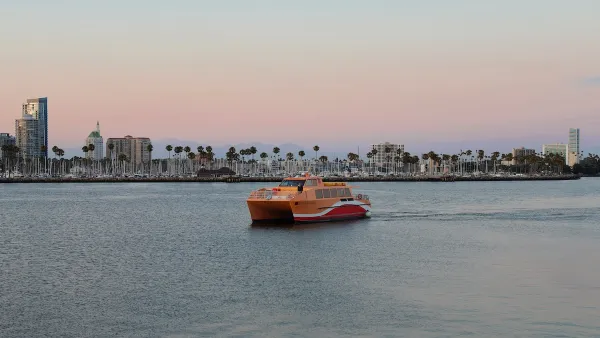 Yellow and red water taxi in Long Beach, California with tall palm trees on beach in background at sunset.