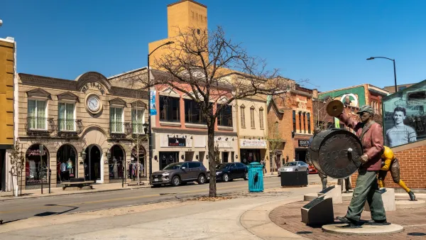 Street in downtown Green Bay, Wisconsin with statue of man beating large drum worn on his chest.