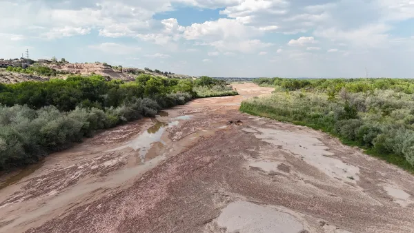 The Rio Grande river, which is reduced to a dirt trail with a few puddles. There is grass on either side of the river.
