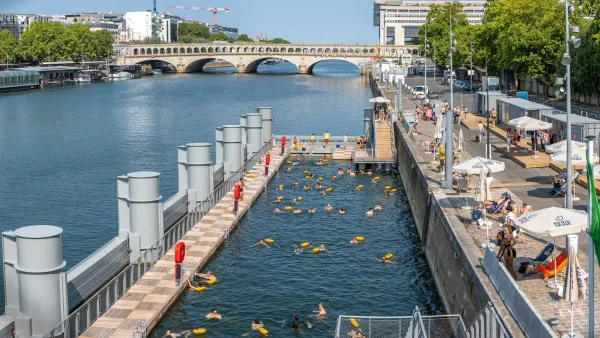 Swimmers in an enclosed swimming area on the Seine River in Paris, France with a low arched bridge visible in background.