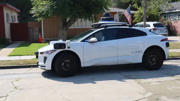 White Waymo autonomous car on small street in Los Angeles.