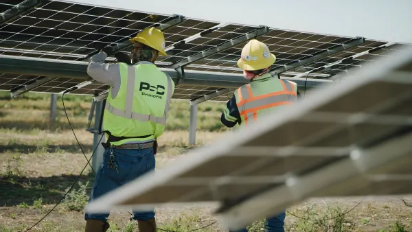 Technicians in green vests Installing Solar Panels at a Solar Farm.