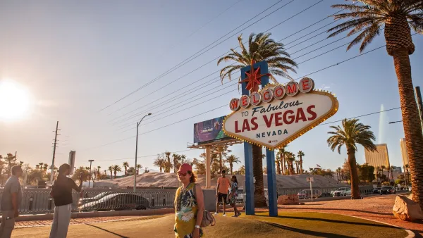 People standing in front of famous Las Vegas sign in warm-toned photo.