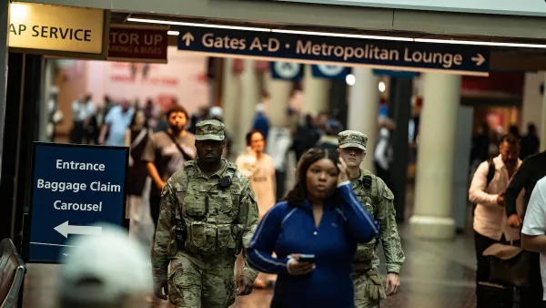 Woman in blue athletic clothes walks through DC Union Station with two National Guardsmen in uniform walking behind her.