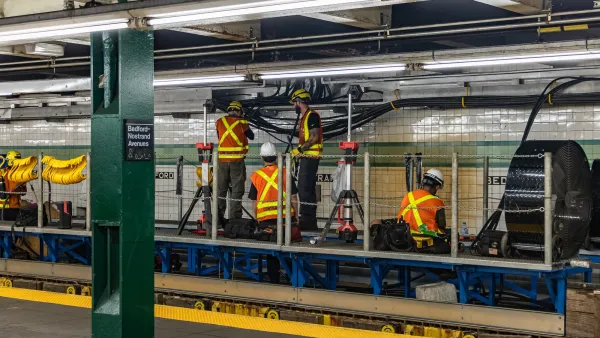 Workers inorange vests working on station infrastructure in New York City subway station.