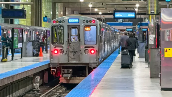A  Chicago 'L' train stands ready at the station as travelers with luggage move about the platform.
