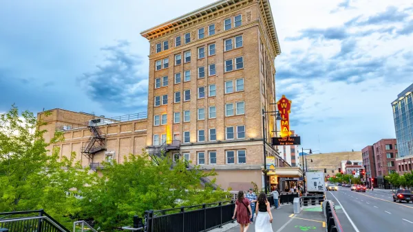 People walking on walkway and bike path next to historic brick building in downtown Missoula, Montana.