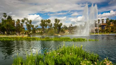 Echo Park Lake with tall artesian fountain, palm trees and apartment buildings in background.