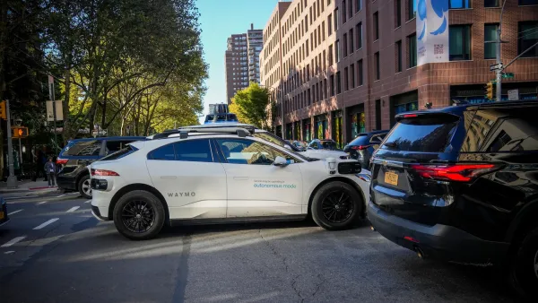 White Waymo SUV in traffic on New York City street.