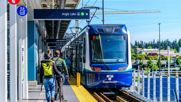 People walking toward blue Sound Transit train at open-air platform in Seattle, Washington.